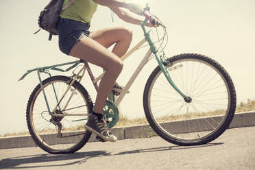 Beine einer jungen Frau beim Fahrradfahren an einem sonnigen Tag - AJOF00236