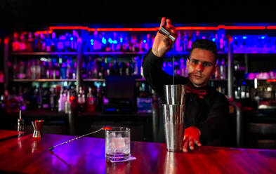 Männlicher Barkeeper, der ein Cocktailgetränk in einem Glas mischt - MGOF04558