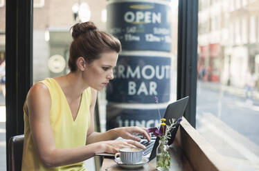 Young businesswoman using laptop at coffee shop - AJOF00257