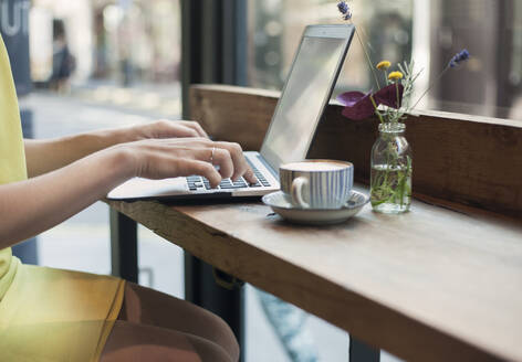 Junge Geschäftsfrau arbeitet an einem Laptop in einem Café - AJOF00259