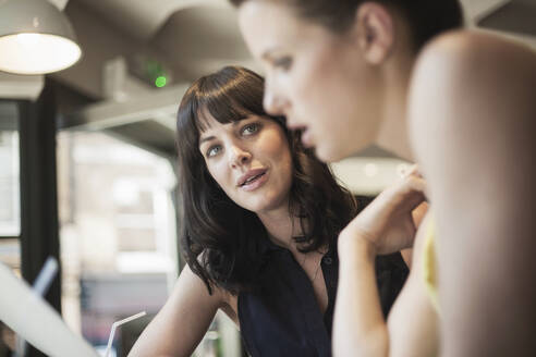 Geschäftsfrauen diskutieren bei einem Treffen in einem Café - AJOF00268