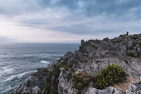 Mann mit Angelrute auf den Klippen von Bufones de Pria in der Abenddämmerung, Asturien, Spanien - JMPF00461