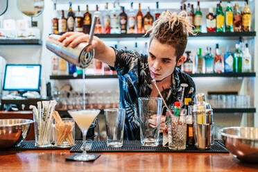 Serious Barkeeper gießt frischen Alkohol Cocktail in Glaspokal auf dem Tresen in der Bar platziert - ADSF16654