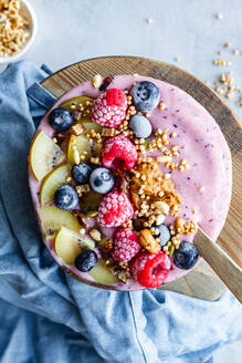 Draufsicht auf eine nahrhafte Frühstücksschüssel mit Beeren und Joghurt, die morgens auf dem Tisch steht - ADSF16664