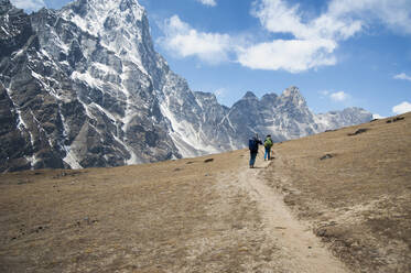 Zwei Bergsteiger auf einem Pfad mit Blick auf die steilen Berge. - MINF15203