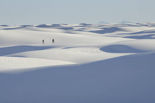 Zwei Menschen, die in einiger Entfernung über weiße Sanddünen gehen. - MINF15205