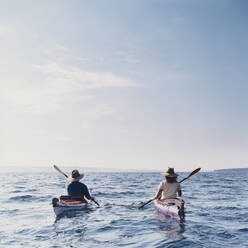 Middle aged man and woman sea kayaking on calm waters - MINF15212