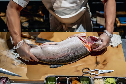 Männlicher Koch putzt Fisch am Tresen eines Restaurants - OCMF01752
