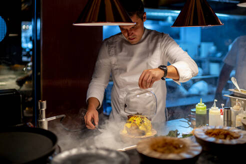 Male chef preparing food in kitchen at restaurant - OCMF01761