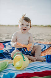 Süßes Baby Junge spielt mit Spielzeug am Strand bei Sonnenuntergang - GMLF00727