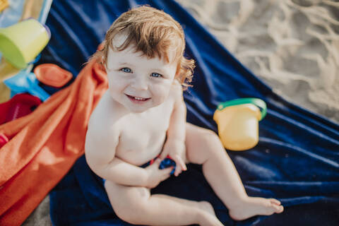 Cute boy smiling while playing at beach on sunny day stock photo