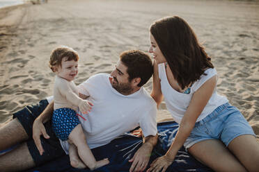 Mann und Frau verbringen Zeit mit Sohn am Strand bei Sonnenuntergang - GMLF00734