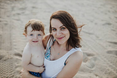 Lächelnde Mutter mit Sohn am Strand stehend - GMLF00737