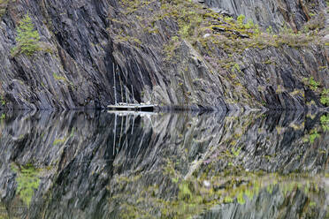 Schieferklippen spiegeln sich in einem klaren, glänzenden See in den schottischen Highlands - ELF02259