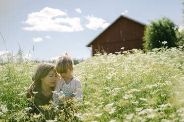 Frau mit Tochter inmitten von Wildblumen, die an einem sonnigen Tag auf einem Feld wachsen - PSIF00402