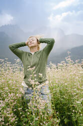 Frau stehend mit Händen hinter dem Kopf inmitten von Pflanzen auf einem Feld - PSIF00413