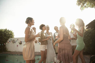 Happy friends enjoying summer while drinking alcohol at poolside against sky - AJOF00285