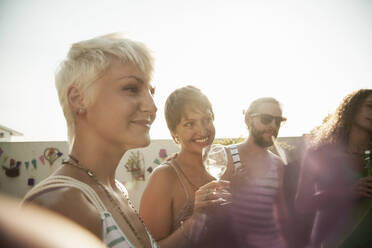 Lächelnde Frauen und Männer genießen die Party beim Trinken gegen den Himmel - AJOF00288
