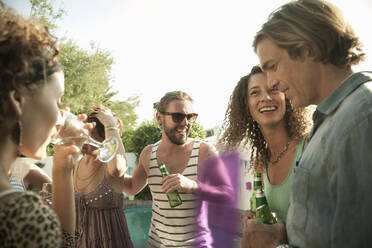 Glückliche männliche und weibliche Freunde genießen den Sommer beim Trinken von Alkohol am Pool gegen den Himmel - AJOF00289