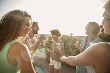 Happy friends dancing while enjoying pool party at sunset - AJOF00294