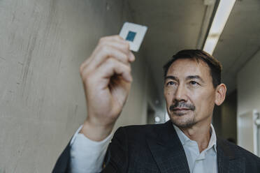 Businessman holding business chip while standing at clinic corridor - MFF06303