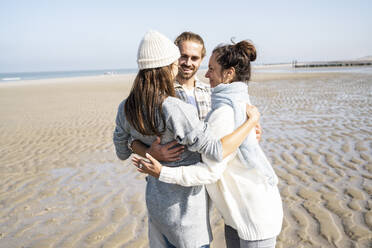 Ehepaar und Mutter stehen mit Arm um am Strand - UUF21674