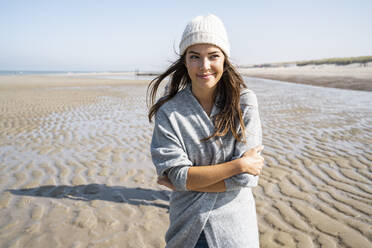 Junge Frau mit verschränkten Armen spazieren gehend mit Mann Schatten im Hintergrund am Strand - UUF21675