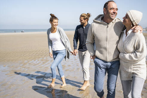 Junges und reifes Paar spazieren zusammen am Strand - UUF21691