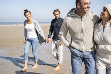 Reifes und junges Paar gehen zusammen am Strand spazieren - UUF21692