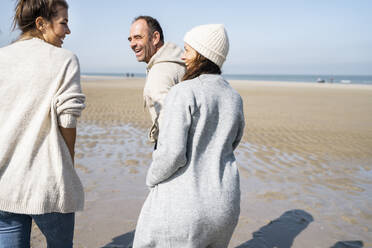 Smiling woman walking with mother and father at beach - UUF21696