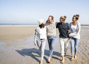 Happy couples with arm around walking at beach - UUF21707