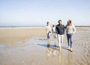 Men walking with women standing in background at beach - UUF21712