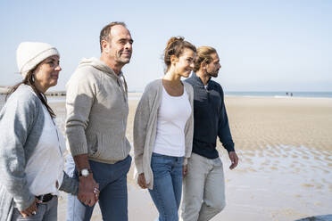 Young and mature couple holding hands while walking at beach - UUF21724