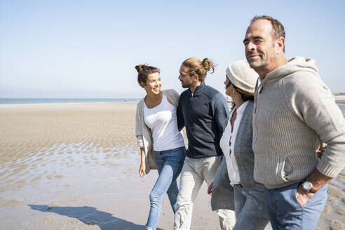 Lächelnde Paare gehen zusammen am Strand - UUF21725