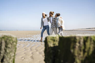 Man and women walking with arm around at beach - UUF21740