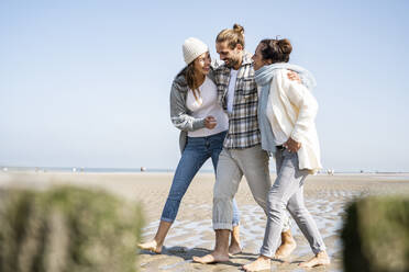 Smiling family talking while walking at beach together - UUF21741