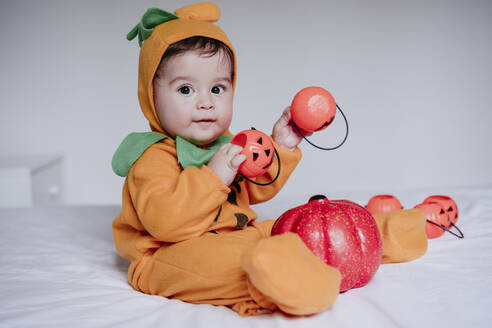 Baby-Junge trägt Halloween-Kostüm spielen mit Kürbis Spielzeug zu Hause sitzen - EBBF00910