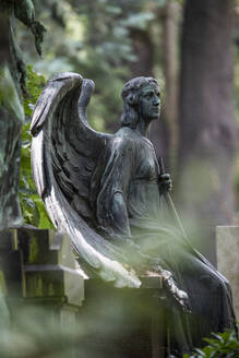 Verwitterte Engelsstatue am Rande eines Grabes auf dem Friedhof - JATF01249