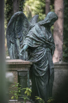 Verwitterte Statue eines Engels neben einem Grab auf dem Friedhof - JATF01251