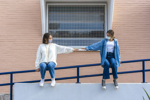 Teenage friends social distancing while sitting on railing during covid-19 - ERRF04581