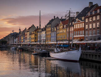 Dänemark, Kopenhagen, Boote an der Nyhavn-Promenade in der Abenddämmerung mit einer Reihe von historischen Stadthäusern im Hintergrund - HAMF00720