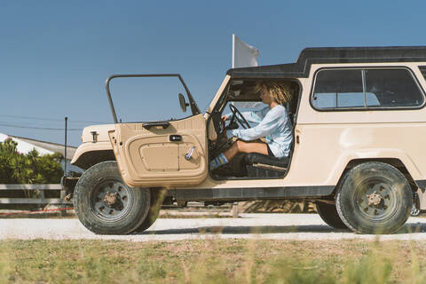 Woman sitting in old off-road vehicle on sunny day stock photo