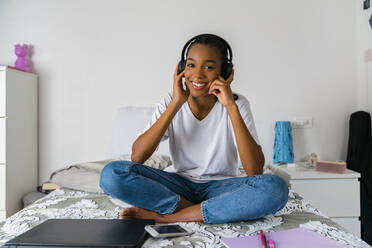 Young girl with cross legged listening to music while sitting at home - MGIF01027