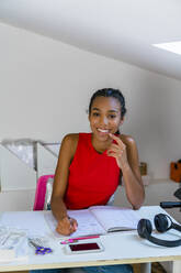 Teenage girl studying while sitting on table at home - MGIF01042