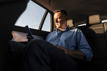 Mature male entrepreneur using smart phone while sitting in car - WPEF03464