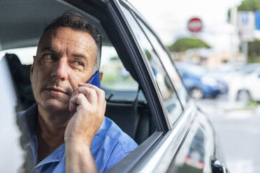 Mature male entrepreneur talking through mobile phone while sitting in car - WPEF03467