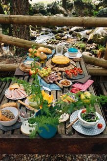 Hohe Winkel der alten Holztisch mit verschiedenen Gerichten für gemütliche Picknick im Wald im Valle del Jerte serviert - ADSF16835