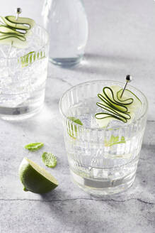 Refreshing Mojito cocktails in glasses with ice cubes arranged on table with lime slices - ADSF16849