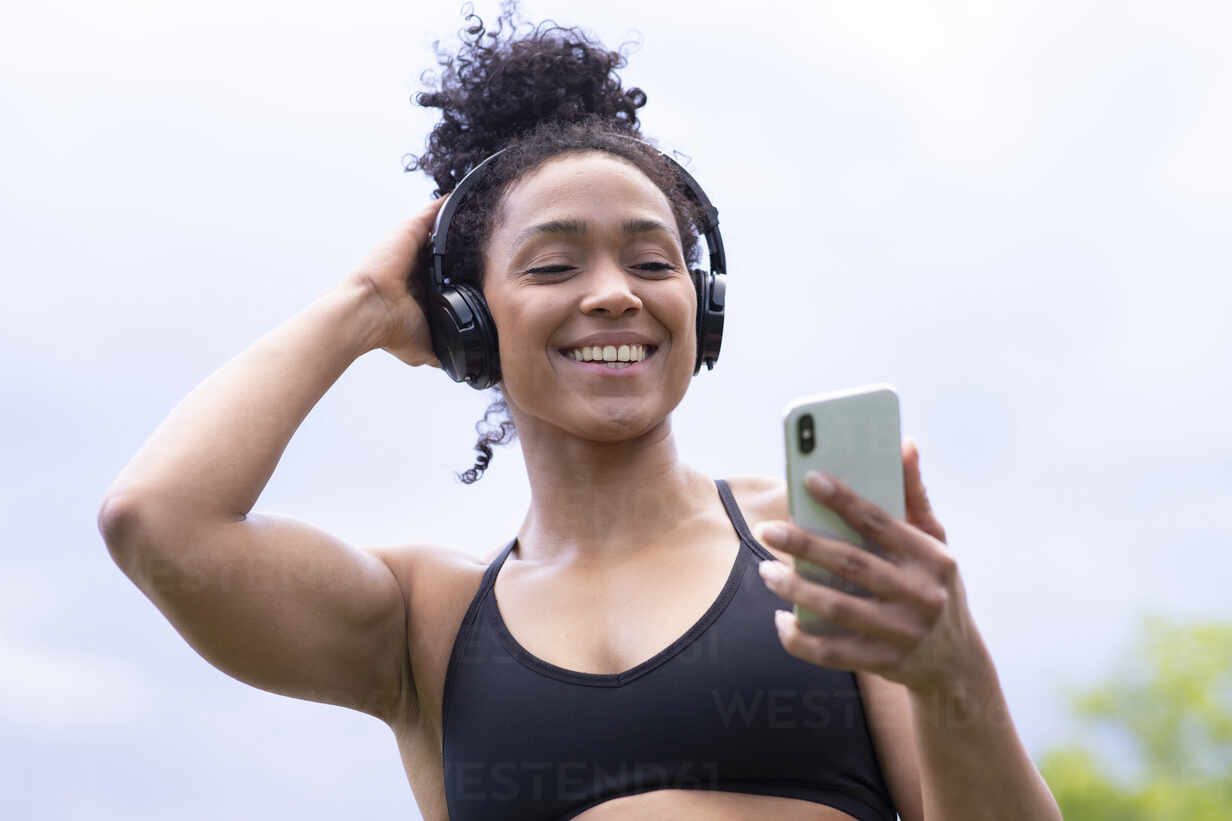 Woman with Headphones and Cell Phone in Sports Bra