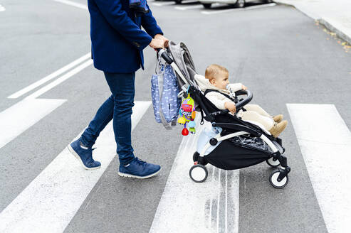 Mann mit Kinderwagen überquert Straße in der Stadt - PGF00153